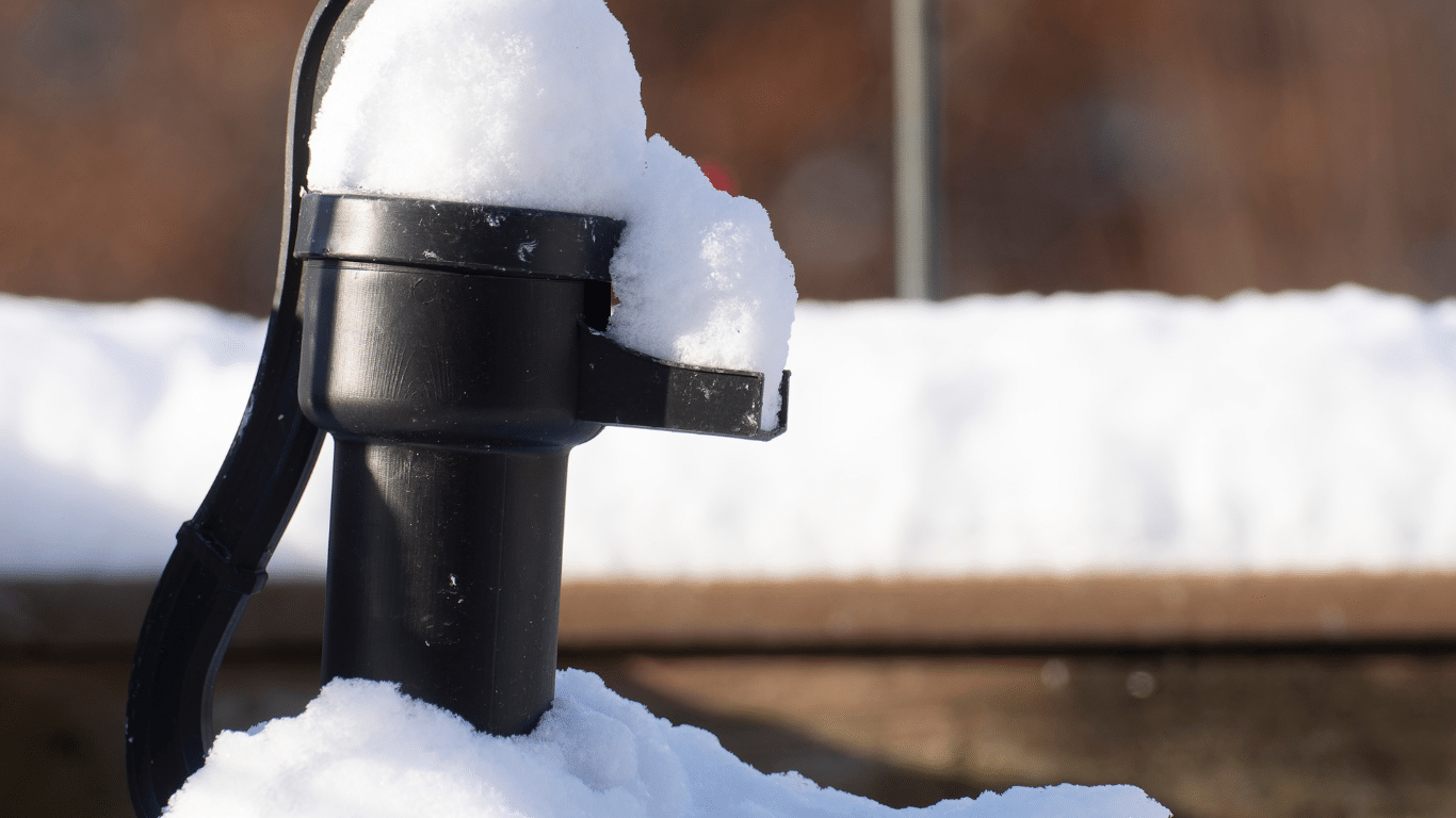 water well pump covered in snow